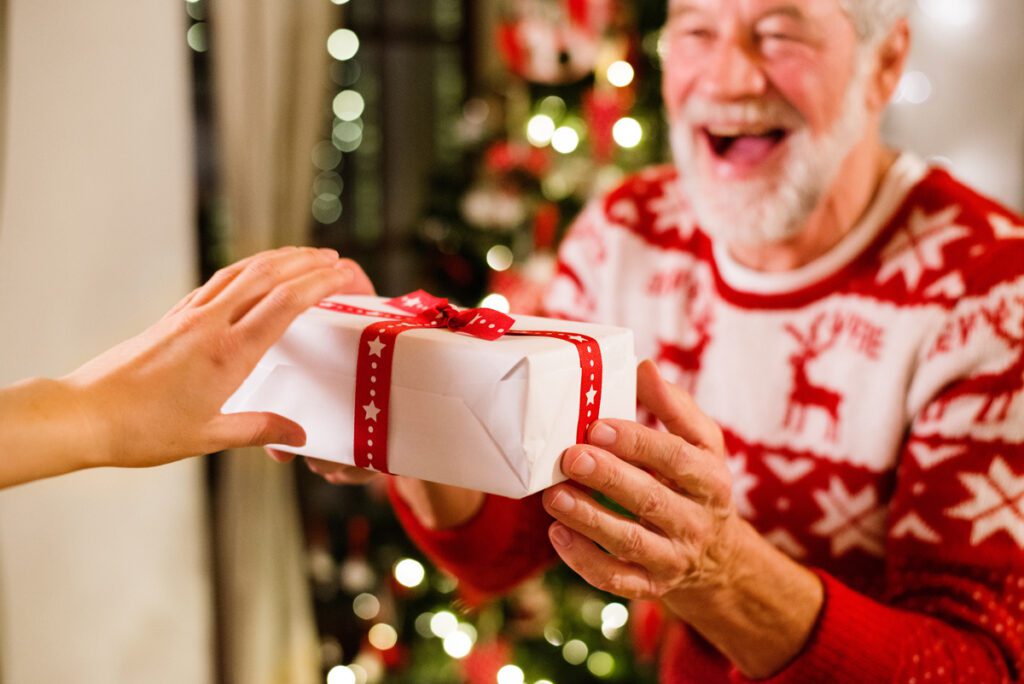 An older man receives a wrapped holiday gift