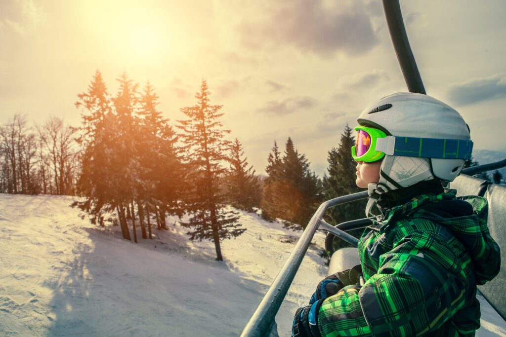 A child rides a ski lift at one of the top family winter vacation destinations