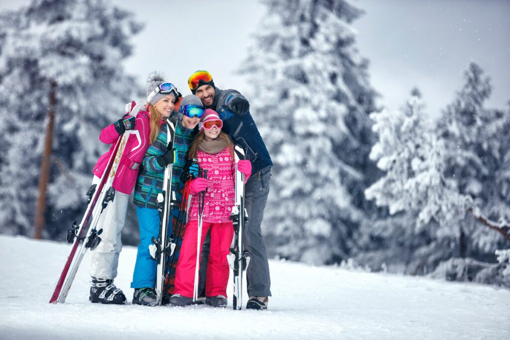 A family skiing in the mountains pose for a photo