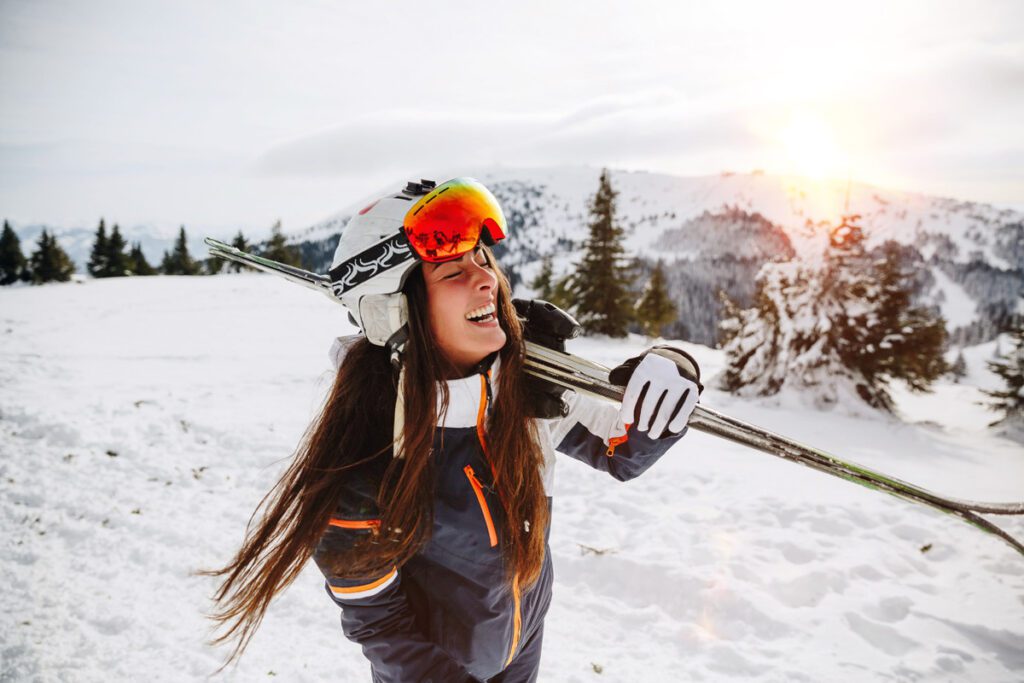 A woman carries skis to the lifts after procuring ski vacation equipment rentals