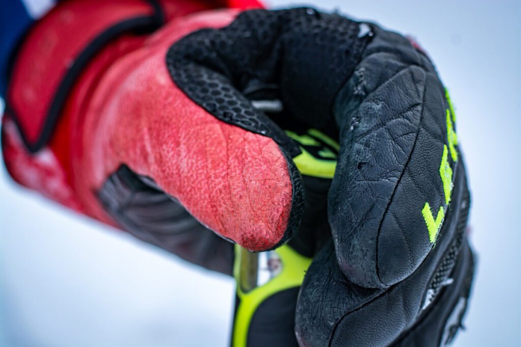 A red and black glove grips a ski pole