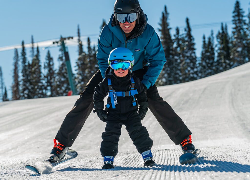 A father and young son ski together.