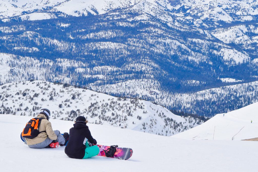 Skiers sit on a mountaintop at a California ski resort