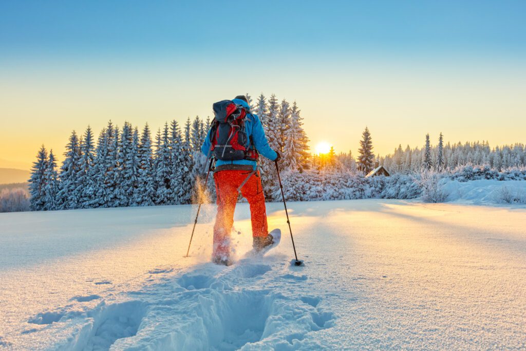 A man goes snowshoeing at sunrise