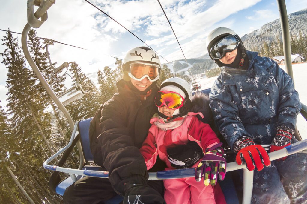 A family rides a ski lift in the spring.