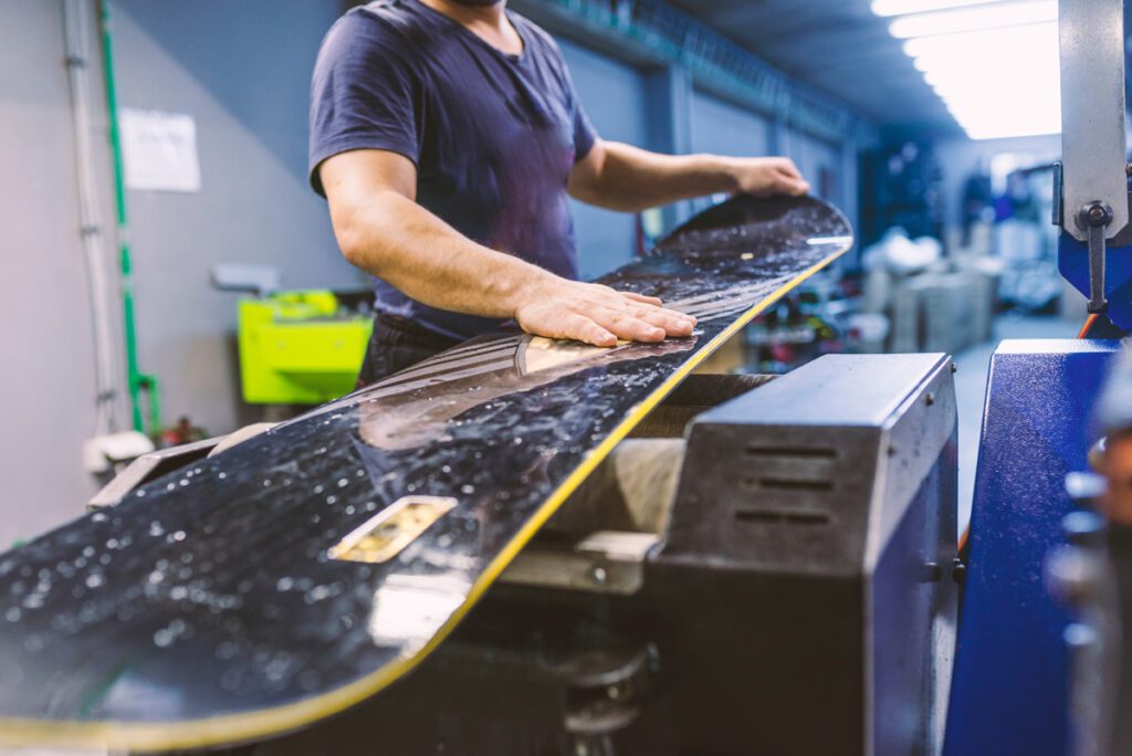 A ski shops preps a snowboard for summer storage