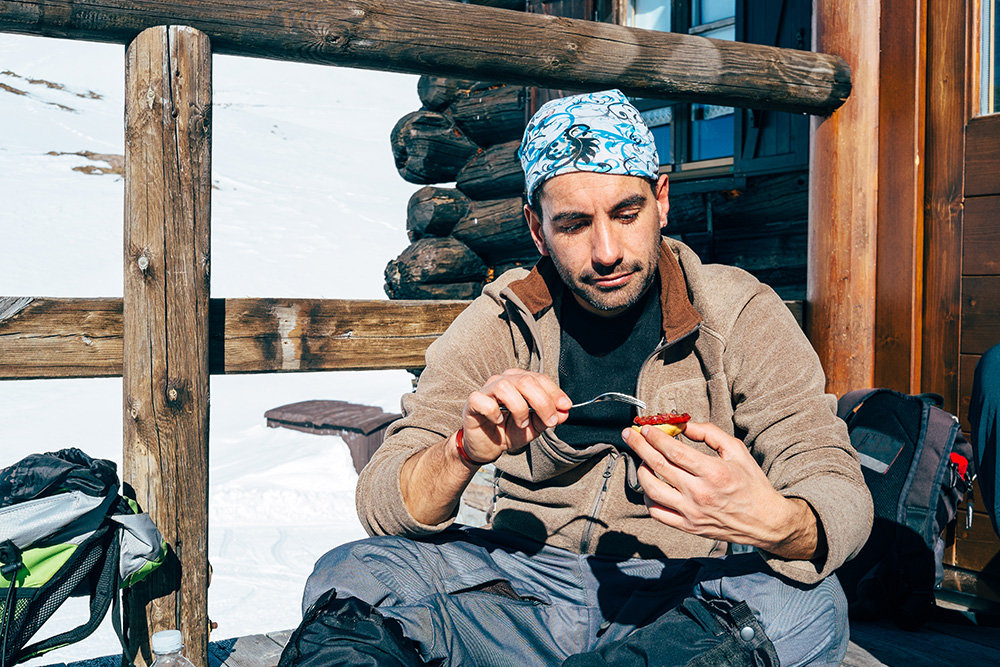A man has a snack on the slopes